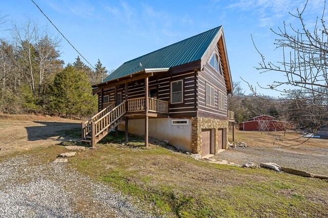 view of front facade featuring metal roof, a garage, stone siding, driveway, and stairway