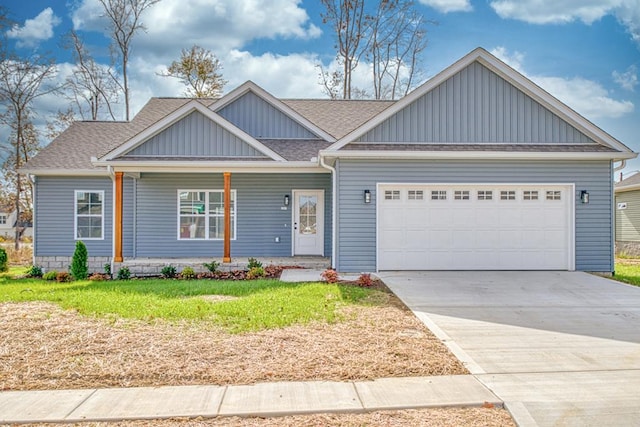 view of front of property featuring an attached garage, driveway, a front yard, and roof with shingles