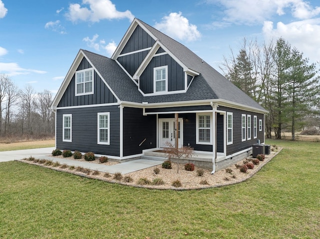 view of front of home with roof with shingles, covered porch, board and batten siding, a front yard, and cooling unit