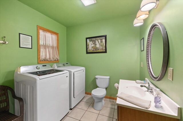 clothes washing area featuring washing machine and dryer, light tile patterned flooring, a sink, laundry area, and baseboards