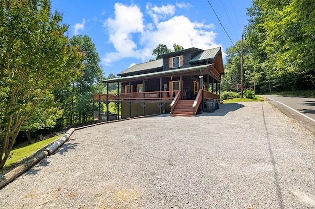 view of front of home featuring covered porch, metal roof, and stairway