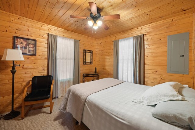 carpeted bedroom featuring a ceiling fan, wood ceiling, electric panel, and wood walls