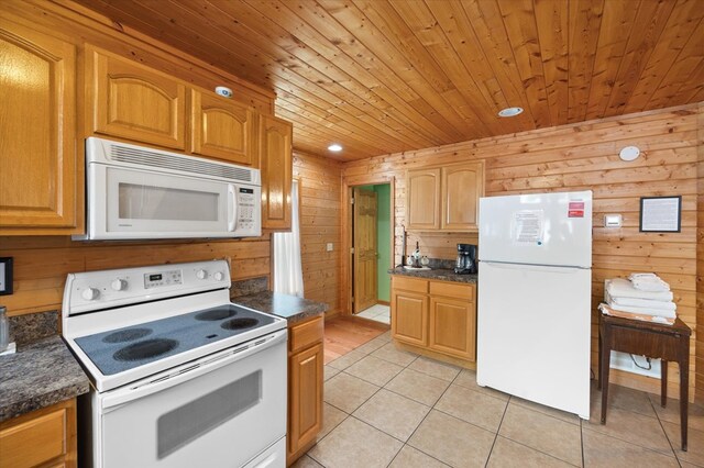 kitchen with light tile patterned floors, wooden ceiling, white appliances, wood walls, and brown cabinetry