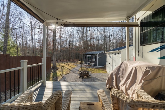 wooden deck with a fire pit, a shed, an outbuilding, and fence