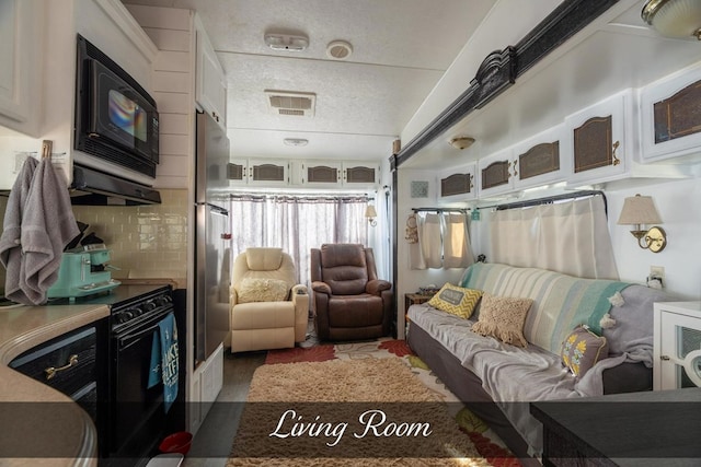 living area with a textured ceiling and visible vents