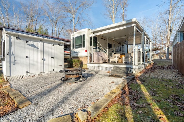 rear view of house with a storage shed, a fire pit, metal roof, a standing seam roof, and an outdoor structure