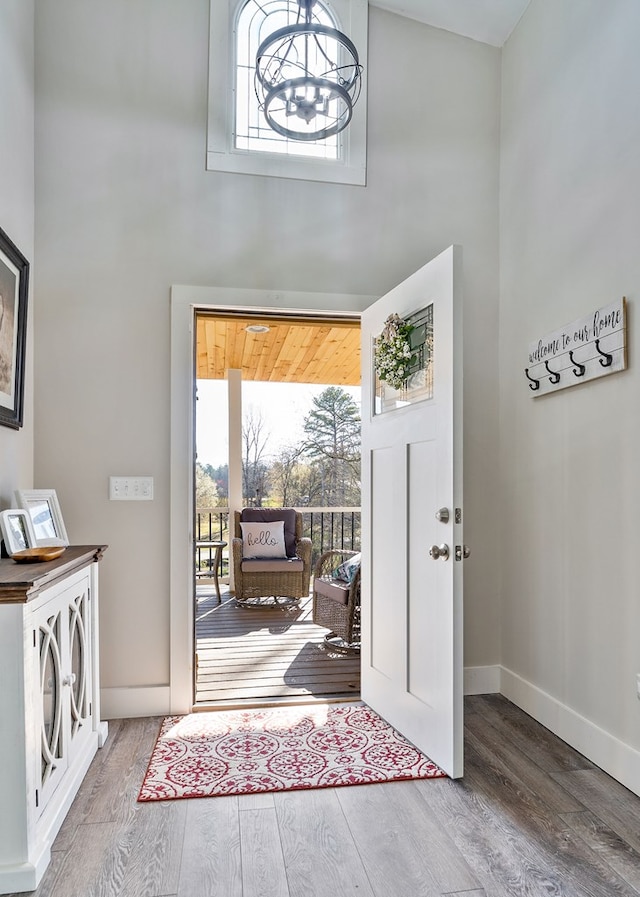 entrance foyer with a wealth of natural light, wood finished floors, baseboards, and a chandelier