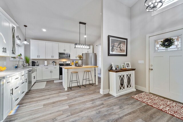 kitchen with white cabinets, a breakfast bar area, appliances with stainless steel finishes, light wood-type flooring, and wood counters
