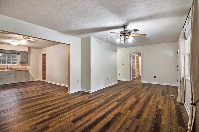 unfurnished living room featuring a textured ceiling, a ceiling fan, dark wood finished floors, and a sink