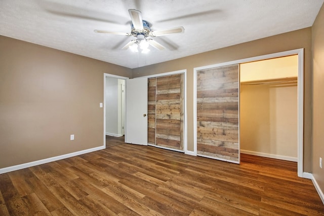 unfurnished bedroom featuring dark wood finished floors, baseboards, and two closets