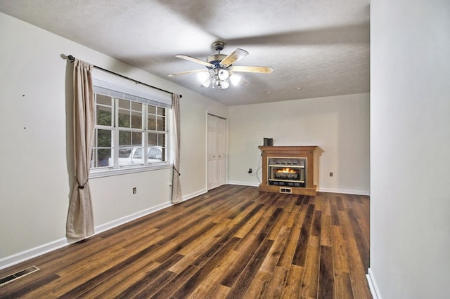 unfurnished living room with a ceiling fan, a glass covered fireplace, dark wood-style flooring, and baseboards