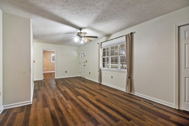 unfurnished room featuring visible vents, dark wood-type flooring, a ceiling fan, a textured ceiling, and baseboards