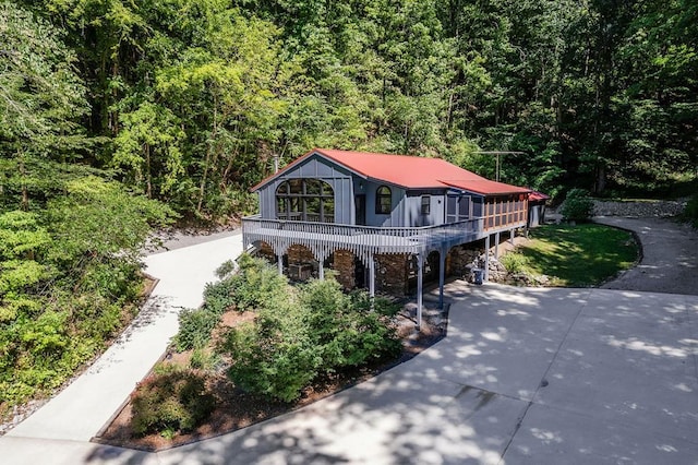 view of front of property with driveway and a wooded view