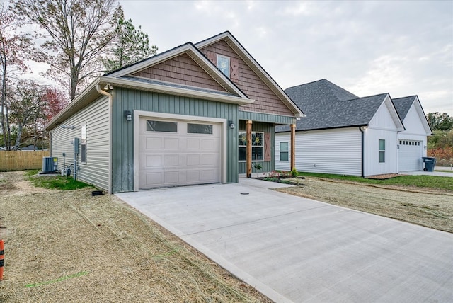 view of front of property featuring a garage, concrete driveway, fence, central air condition unit, and a front lawn