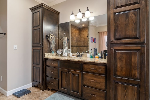 bathroom with vanity, crown molding, baseboards, and tiled shower