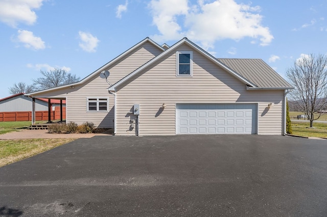 view of front of property featuring aphalt driveway, a garage, and metal roof