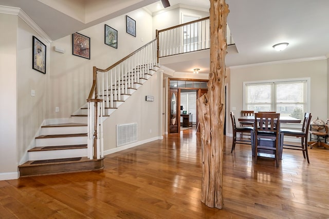 interior space featuring visible vents, stairway, crown molding, and hardwood / wood-style flooring