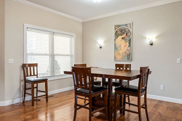 dining space featuring crown molding, baseboards, and hardwood / wood-style flooring