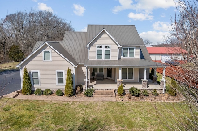 view of front of property with a front yard, covered porch, and metal roof