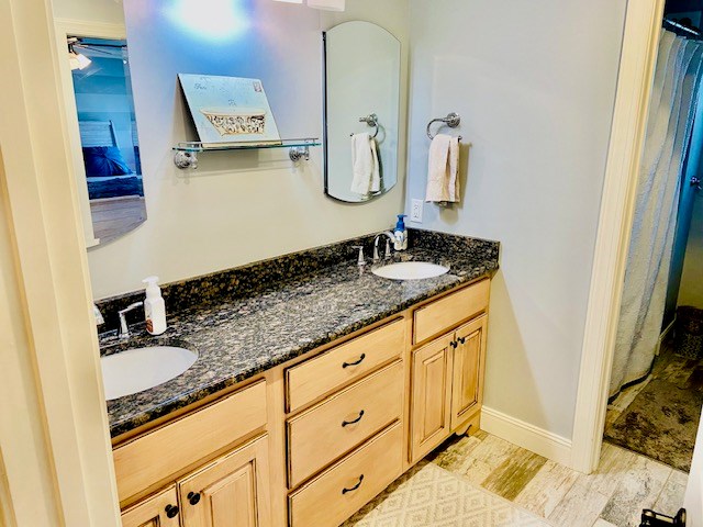 full bath featuring a sink, baseboards, and double vanity