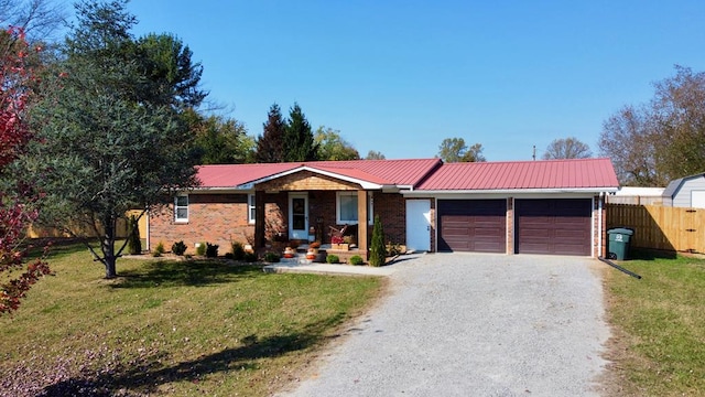 ranch-style home featuring metal roof, a front lawn, an attached garage, and driveway