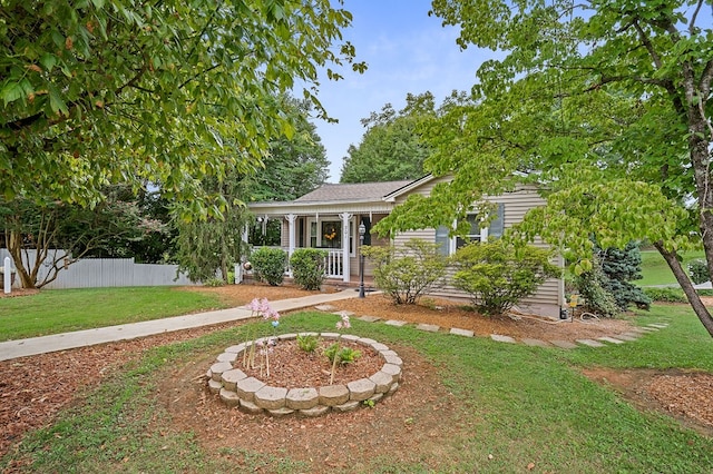 view of property hidden behind natural elements featuring a front yard, covered porch, and fence