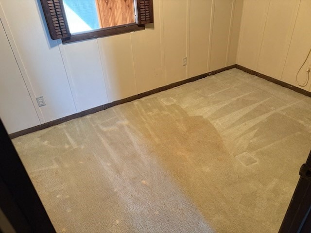 empty room featuring light carpet and a decorative wall