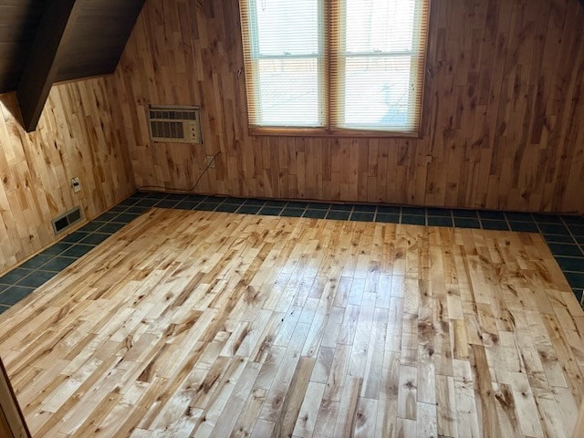 additional living space featuring visible vents, wooden walls, light wood finished floors, and a wall mounted AC