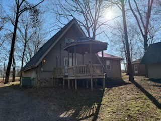 rear view of property featuring cooling unit, a deck, and a gazebo