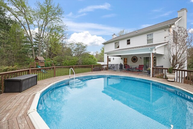 view of pool featuring a deck and a playground