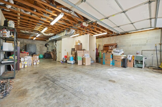 garage featuring a wood stove, concrete block wall, and a garage door opener