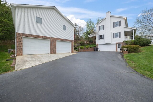 view of side of home with a garage, aphalt driveway, cooling unit, and brick siding