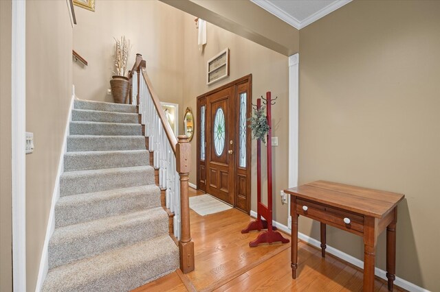 entrance foyer with baseboards, stairs, ornamental molding, and wood finished floors