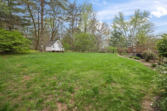 view of yard featuring an outdoor structure, fence, a wooden deck, and a storage shed