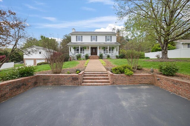 view of front of home with covered porch, fence, and a front lawn