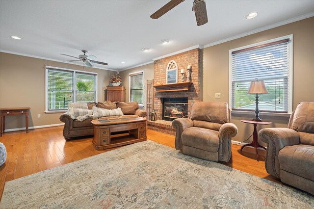 living room with a brick fireplace, light wood-style flooring, ornamental molding, and baseboards