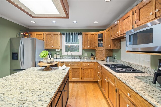 kitchen featuring stainless steel appliances, a sink, glass insert cabinets, and crown molding