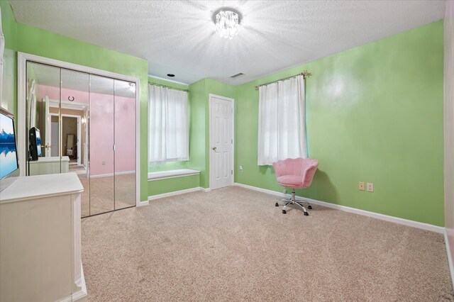 interior space featuring a closet, visible vents, light carpet, a textured ceiling, and baseboards