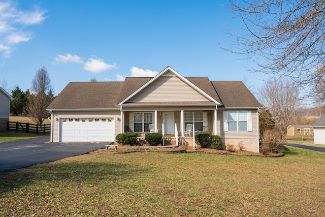 view of front of property with driveway, a porch, fence, a front yard, and an attached garage