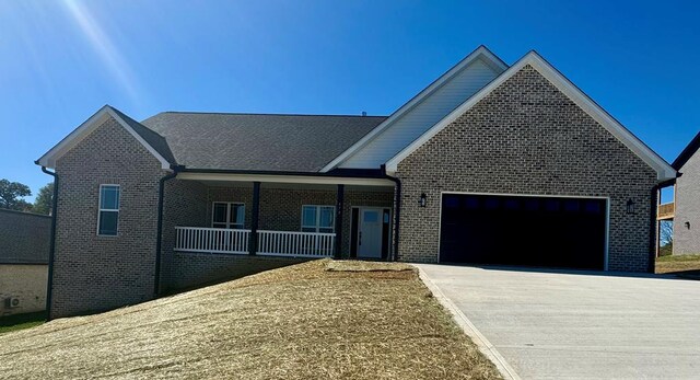 view of front of property featuring an attached garage, covered porch, concrete driveway, and brick siding