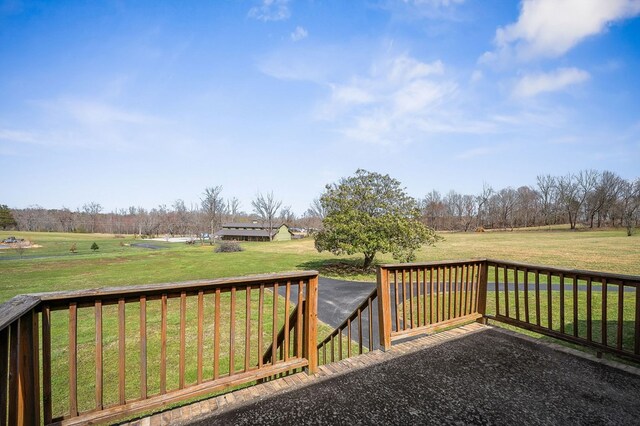 wooden terrace featuring a yard and a rural view