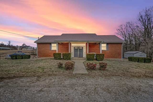 view of front facade featuring metal roof, a lawn, and brick siding