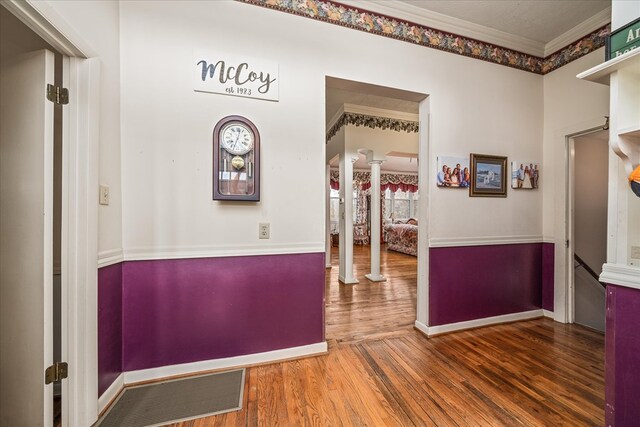 hall featuring ornamental molding, baseboards, ornate columns, and wood finished floors