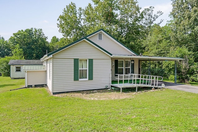 rear view of house with a yard, a porch, an outdoor structure, and driveway