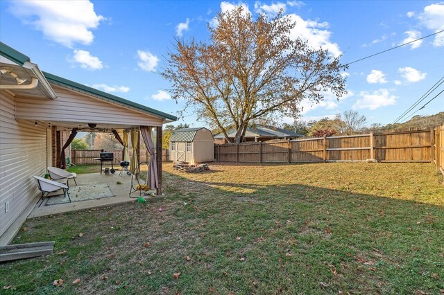 view of yard featuring an outbuilding, a patio, a storage unit, and a fenced backyard