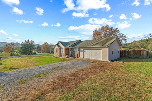 ranch-style home featuring gravel driveway, an attached garage, a front yard, fence, and metal roof