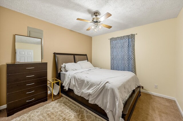 bedroom featuring light carpet, ceiling fan, a textured ceiling, and baseboards