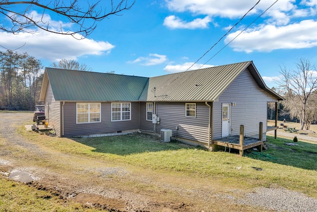 back of property featuring central AC, metal roof, and a lawn