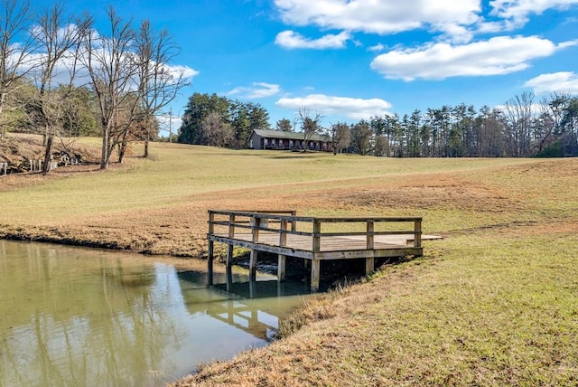 view of dock featuring a rural view, a lawn, and a water view