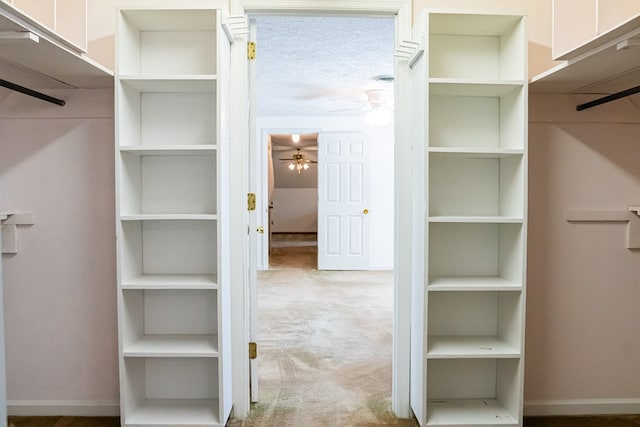 spacious closet featuring ceiling fan and light colored carpet